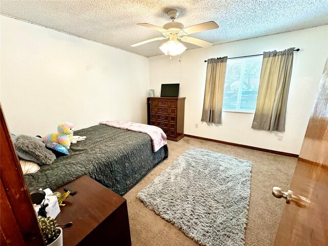 carpeted bedroom featuring ceiling fan and a textured ceiling