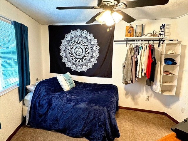 carpeted bedroom with ceiling fan and a textured ceiling