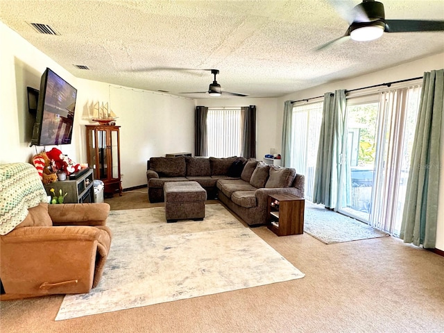 carpeted living room featuring ceiling fan and a textured ceiling