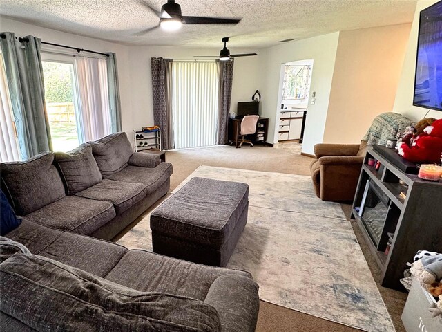 carpeted living room with ceiling fan and a textured ceiling