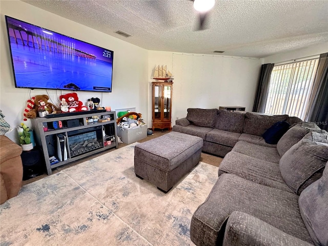 living room featuring ceiling fan and a textured ceiling