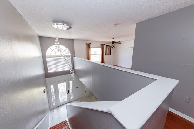 foyer entrance with wood-type flooring, ceiling fan, and a textured ceiling