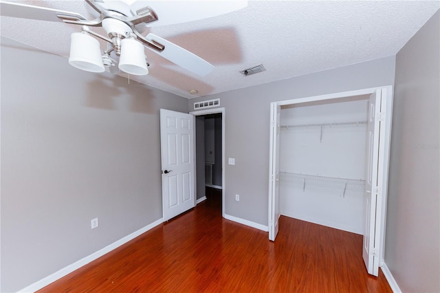 unfurnished bedroom with a closet, ceiling fan, a textured ceiling, and dark hardwood / wood-style flooring