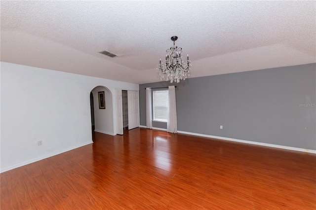 unfurnished room featuring a notable chandelier, a textured ceiling, and hardwood / wood-style floors