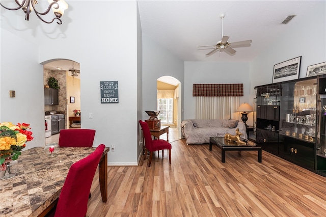 107 Needlewood Loop, Debary, FL 32713 - living room featuring arched walkways, light wood-type flooring, a ceiling fan, a chandelier, and a high ceiling