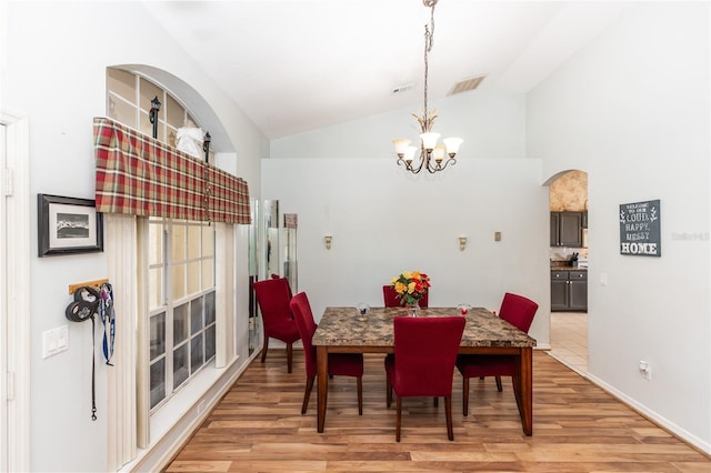 dining space with light wood-type flooring, lofted ceiling, and a notable chandelier