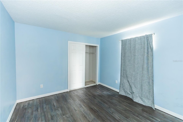 unfurnished bedroom featuring a closet, dark hardwood / wood-style floors, and a textured ceiling