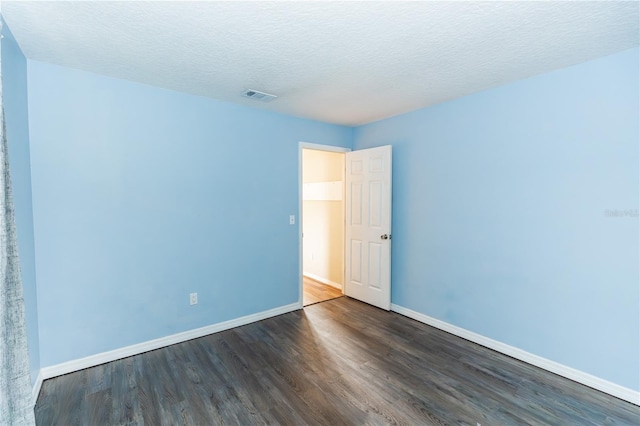 spare room featuring a textured ceiling and dark hardwood / wood-style flooring