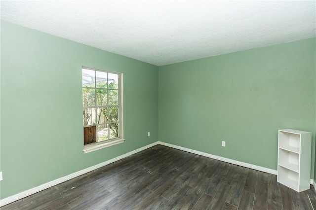 spare room with a textured ceiling and dark hardwood / wood-style floors