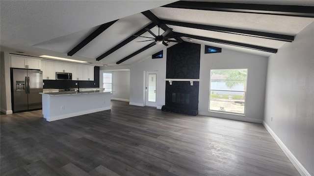 kitchen with white cabinets, dark hardwood / wood-style flooring, appliances with stainless steel finishes, a textured ceiling, and vaulted ceiling with beams