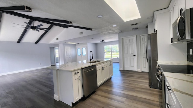 kitchen with appliances with stainless steel finishes, white cabinetry, a kitchen island with sink, vaulted ceiling with beams, and dark hardwood / wood-style floors