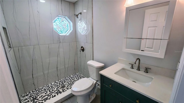 bathroom with vanity, toilet, and tiled shower