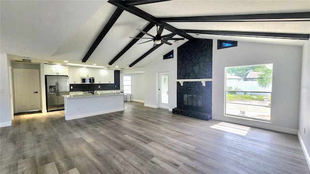 kitchen with wood-type flooring, a fireplace, ceiling fan, stainless steel appliances, and white cabinets