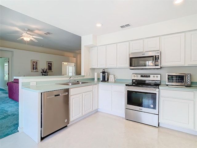 kitchen featuring appliances with stainless steel finishes, kitchen peninsula, white cabinetry, and sink