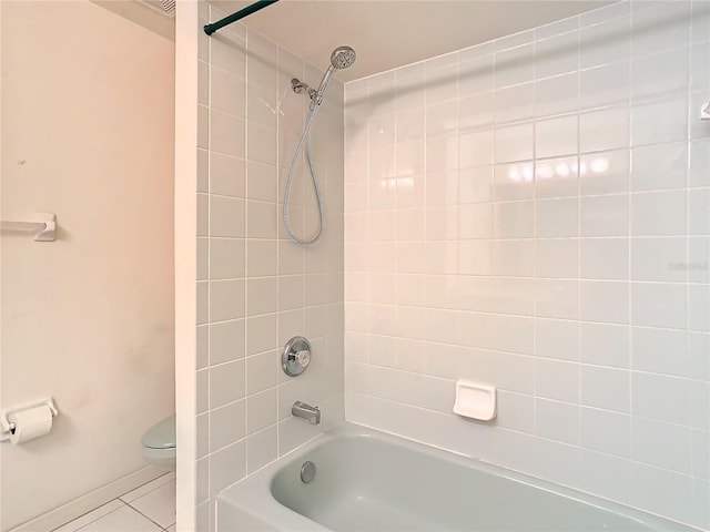 bathroom featuring tiled shower / bath, tile patterned floors, and toilet