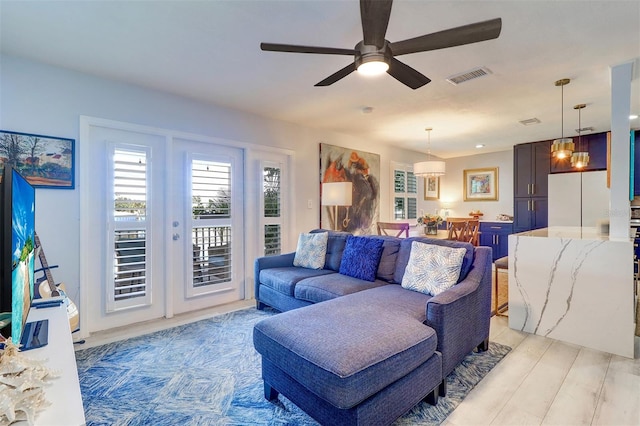 living room with ceiling fan and light hardwood / wood-style flooring