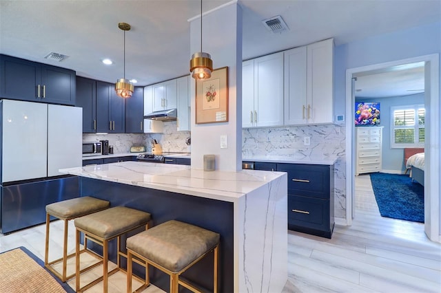 kitchen featuring hanging light fixtures, stainless steel appliances, a center island, light stone countertops, and light hardwood / wood-style floors