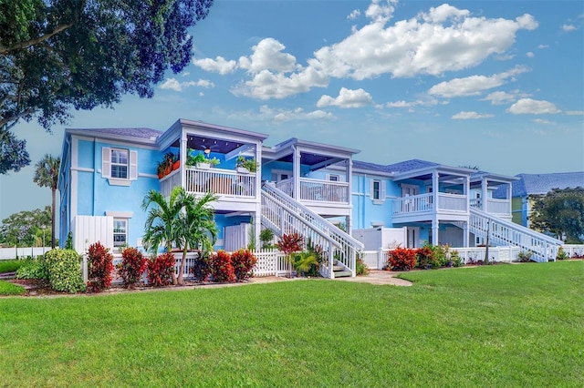 back of house featuring a lawn and a balcony