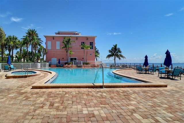 view of pool featuring a patio, a community hot tub, and a water view