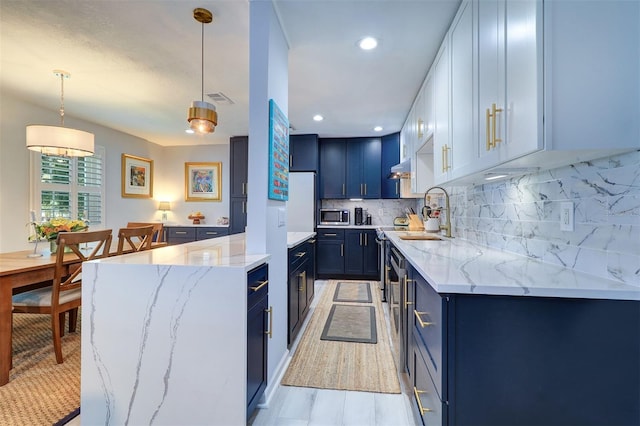 kitchen featuring blue cabinets, sink, light stone countertops, and pendant lighting