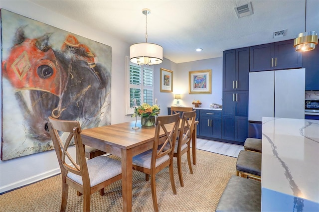 dining area featuring a textured ceiling and light wood-type flooring