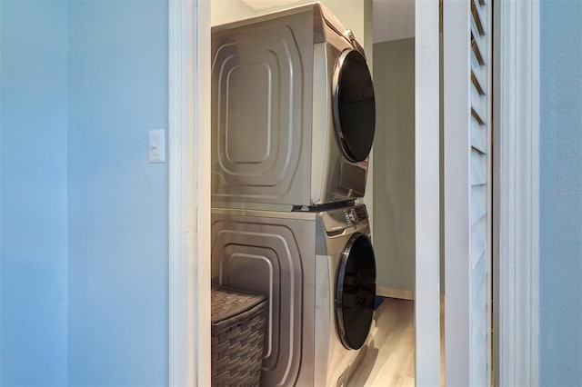 laundry area featuring stacked washing maching and dryer and light hardwood / wood-style flooring