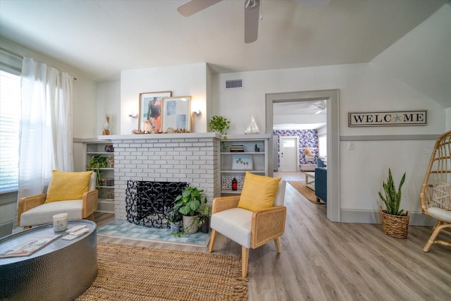 living room with light hardwood / wood-style flooring, ceiling fan, and a fireplace