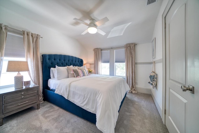 bedroom featuring multiple windows, lofted ceiling with skylight, ceiling fan, and light colored carpet