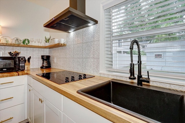 kitchen featuring white cabinets, wooden counters, ventilation hood, black appliances, and sink