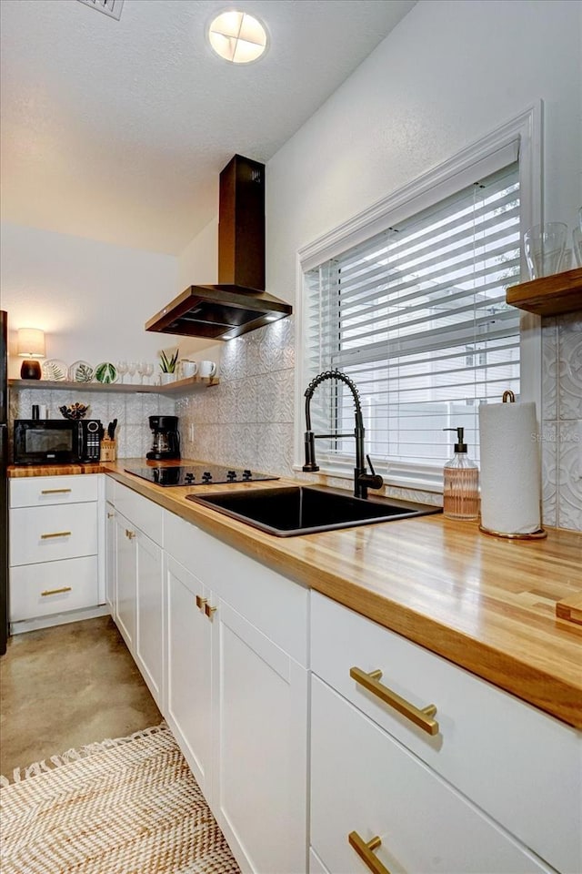 kitchen with white cabinets, island range hood, butcher block counters, black appliances, and sink