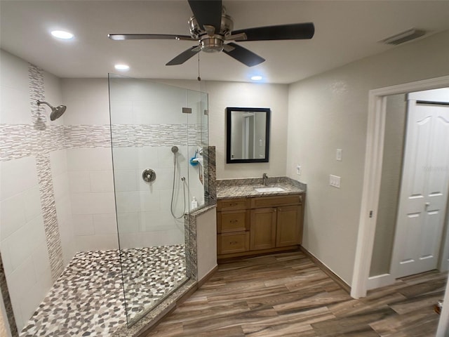 bathroom featuring ceiling fan, tiled shower, vanity, and hardwood / wood-style floors