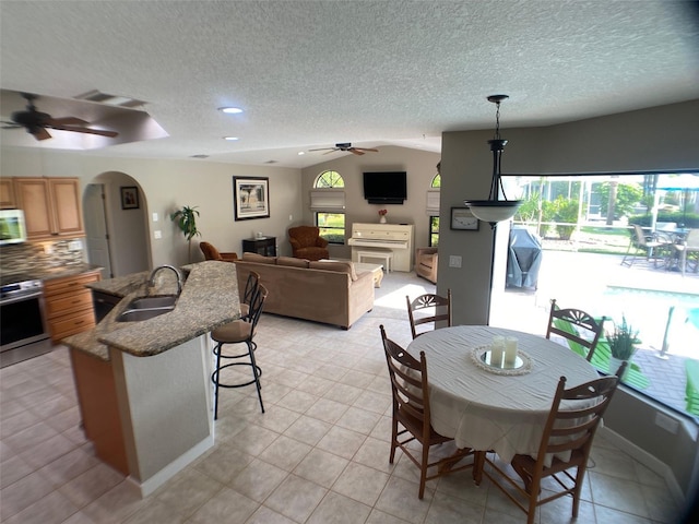 dining space featuring sink, a textured ceiling, vaulted ceiling, ceiling fan, and light tile patterned floors