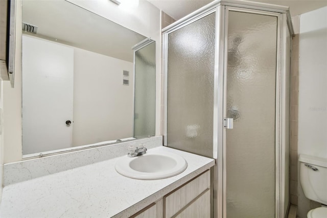 bathroom with toilet, vanity, and a shower with shower door