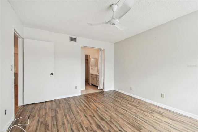 unfurnished bedroom with a textured ceiling, light hardwood / wood-style flooring, ceiling fan, and ensuite bath