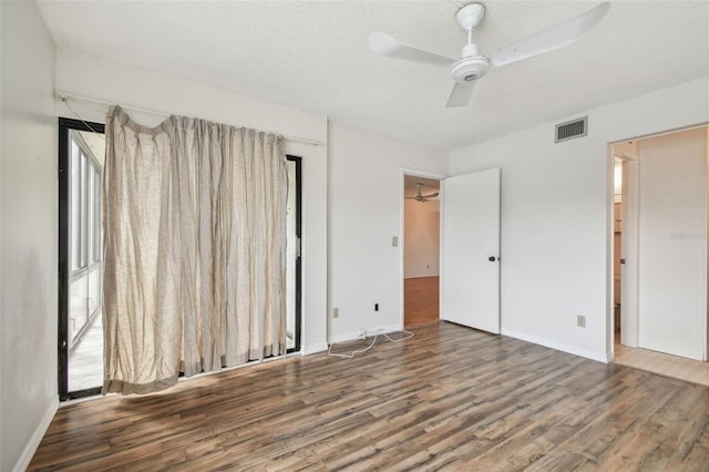 unfurnished bedroom with dark wood-type flooring, a textured ceiling, and ceiling fan