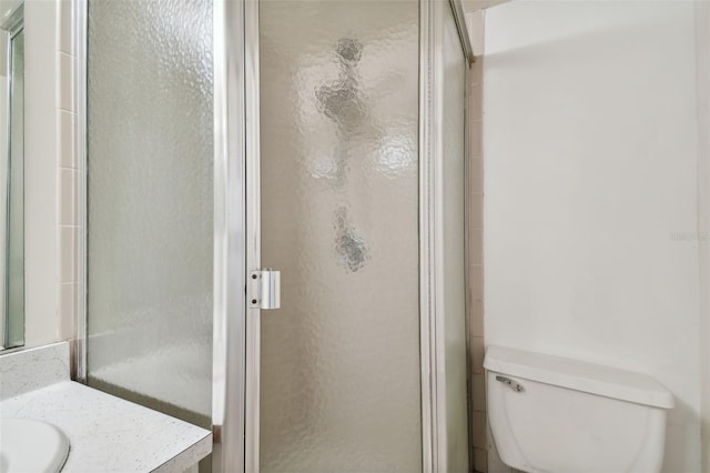 bathroom featuring toilet, vanity, and a shower with door