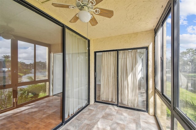 unfurnished sunroom featuring ceiling fan and plenty of natural light