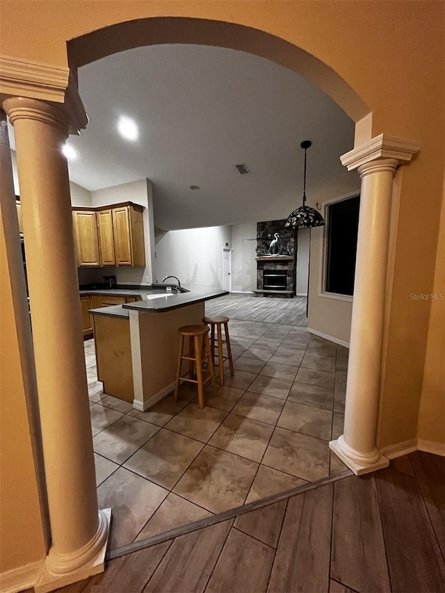 kitchen with light tile patterned floors, sink, a fireplace, and a breakfast bar area