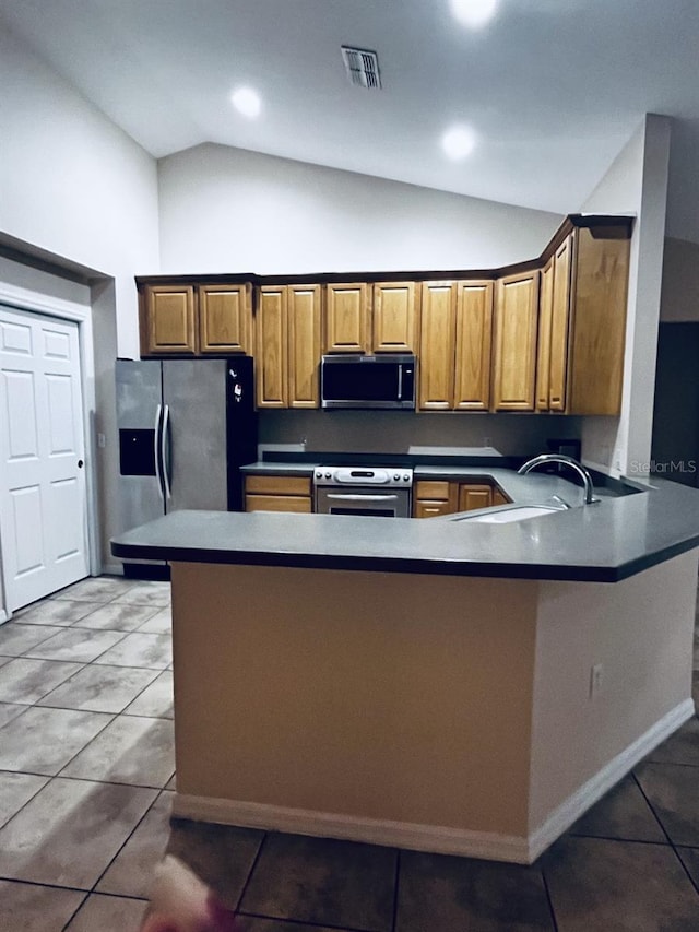 kitchen featuring kitchen peninsula, stainless steel appliances, lofted ceiling, tile patterned flooring, and sink