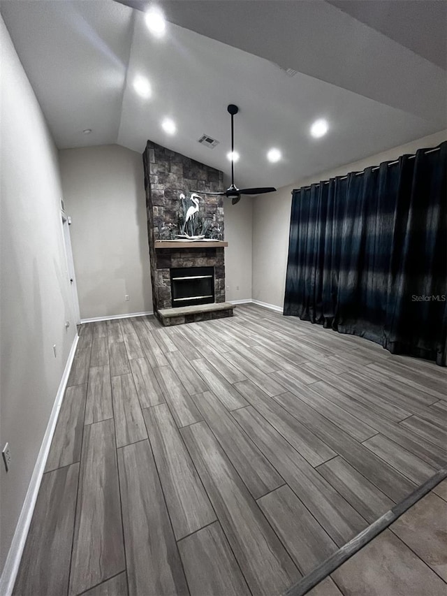 unfurnished living room with ceiling fan, hardwood / wood-style flooring, lofted ceiling, and a fireplace