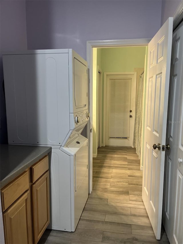 laundry room featuring light hardwood / wood-style flooring and stacked washing maching and dryer