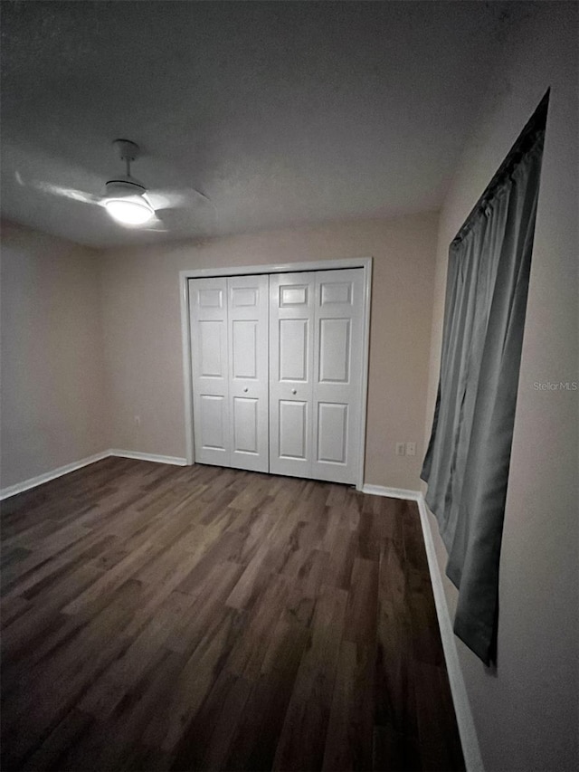 unfurnished bedroom with dark wood-type flooring, ceiling fan, and a closet