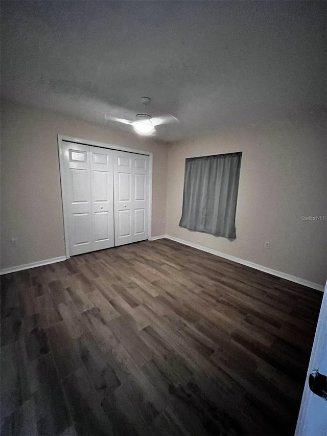 unfurnished bedroom featuring a closet, ceiling fan, and dark wood-type flooring