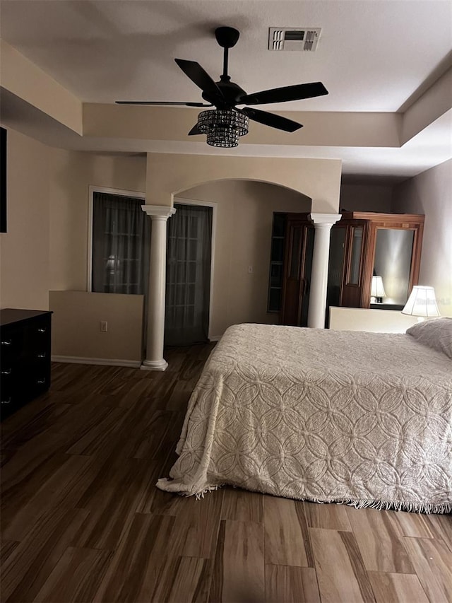 bedroom featuring decorative columns, ceiling fan, and dark wood-type flooring