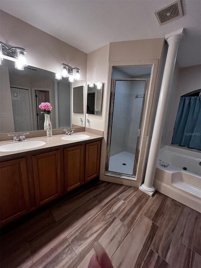 bathroom featuring decorative columns, vanity, hardwood / wood-style floors, and plus walk in shower