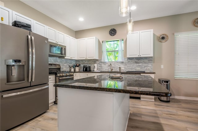 kitchen with appliances with stainless steel finishes, a center island, light hardwood / wood-style flooring, and white cabinets