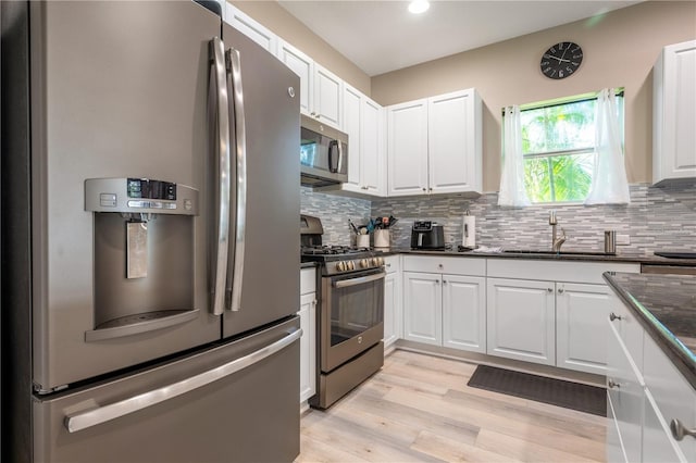 kitchen featuring sink, white cabinets, light hardwood / wood-style flooring, backsplash, and appliances with stainless steel finishes