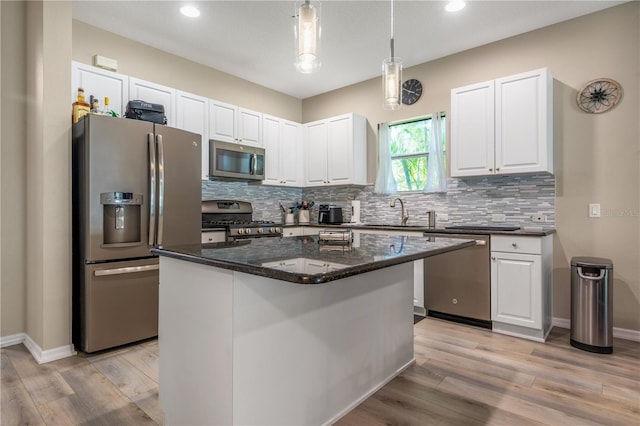 kitchen with appliances with stainless steel finishes, white cabinetry, a center island, and light hardwood / wood-style flooring