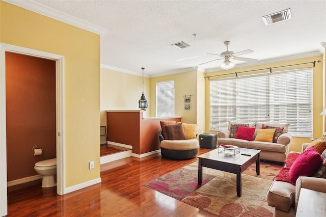 living room with ceiling fan, crown molding, wood-type flooring, and a textured ceiling