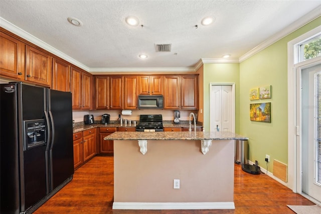 kitchen with stone counters, a kitchen breakfast bar, black appliances, dark wood-type flooring, and a center island with sink